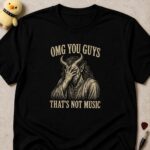 Black t-shirt printed OMG YOU GUYS THAT'S NOT MUSIC around a horned devil covering his face with his hand