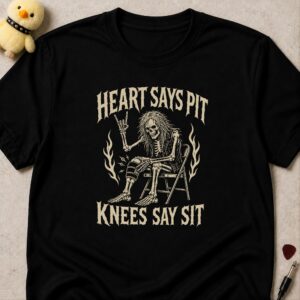 Black t-shirt printed HEART SAYS PIT above and KNEES SAY SIT below a skeleton throwing devil horns from a folding chair