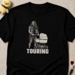 Black t-shirt printed TOURING below a tattooed long-haired man pushing a pram