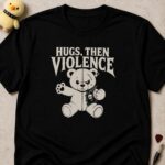 Black t-shirt printed HUGS, THEN VIOLENCE above a stitched teddy bear in a battle vest raising a paw