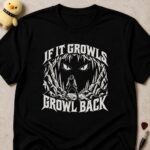 Black t-shirt printed IF IT GROWLS GROWL BACK around a lone figure standing in the jaws of a huge beast