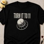 Black t-shirt printed TURN IT TO 11 above an amplifier knob turned past the last mark