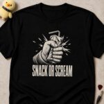 Black t-shirt printed SNACK OR SCREAM below a fist crushing a juice carton