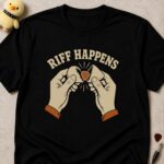 Black t-shirt printed RIFF HAPPENS above two hands snapping a guitar pick in half