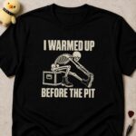 Black t-shirt printed I WARMED UP BEFORE THE PIT around a skeleton in boots stretching over a flight case
