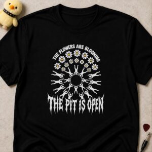 Black t-shirt printed THE FLOWERS ARE BLOOMING THE PIT IS OPEN around a circle pit of figures drawn as daisy petals