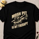 Black t-shirt printed MOSH PIT IS MY THERAPY in cream lettering around a long-haired moshing man mid kick