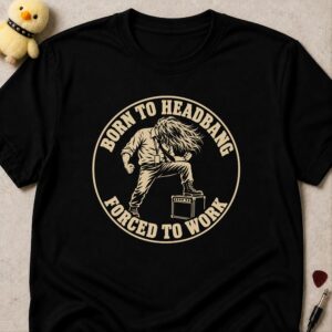 Black t-shirt printed BORN TO HEADBANG FORCED TO WORK in a cream circle around a headbanging office worker with one foot on an amp